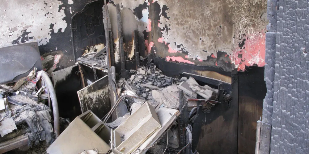 Verrußte Wand und Decke nach einem Wohnungsbrand, vor der Sanierung